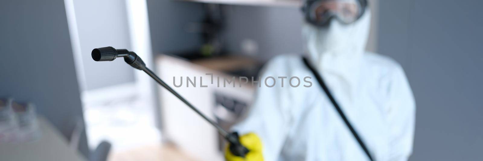 Person in protective suit and mask disinfects kitchen by kuprevich