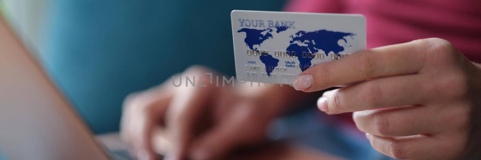 Woman holds bank card in hands and enters data into laptop closeup by kuprevich