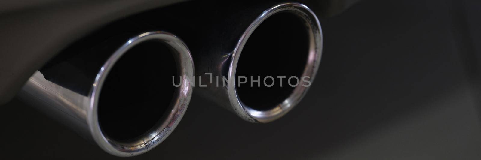 Twin chrome tailpipe of powerful sports car with black body and gray plastic parts by kuprevich