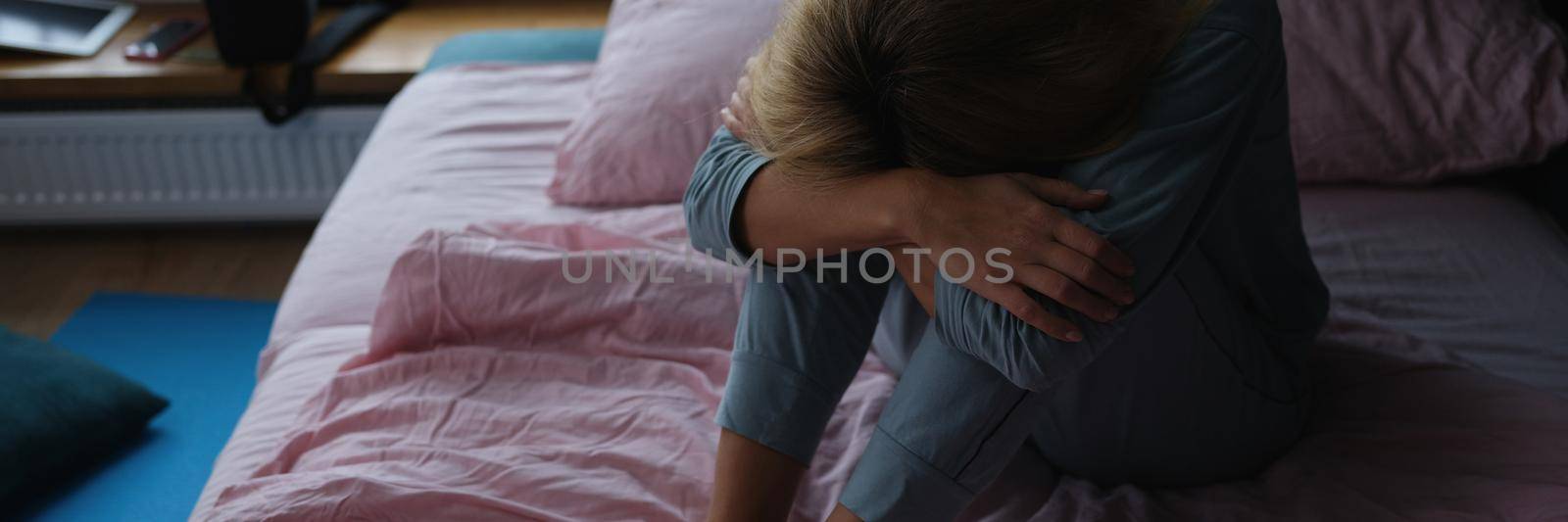 Lonely sad woman sits on bed. Causes of female loneliness concept