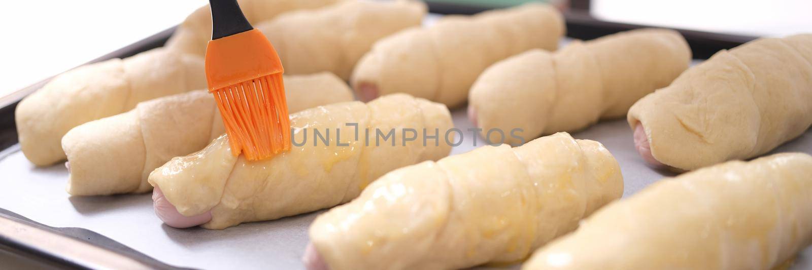 Female chef applies brush of egg yolk to croissants. Egg-based lubricating compound for flour products concept