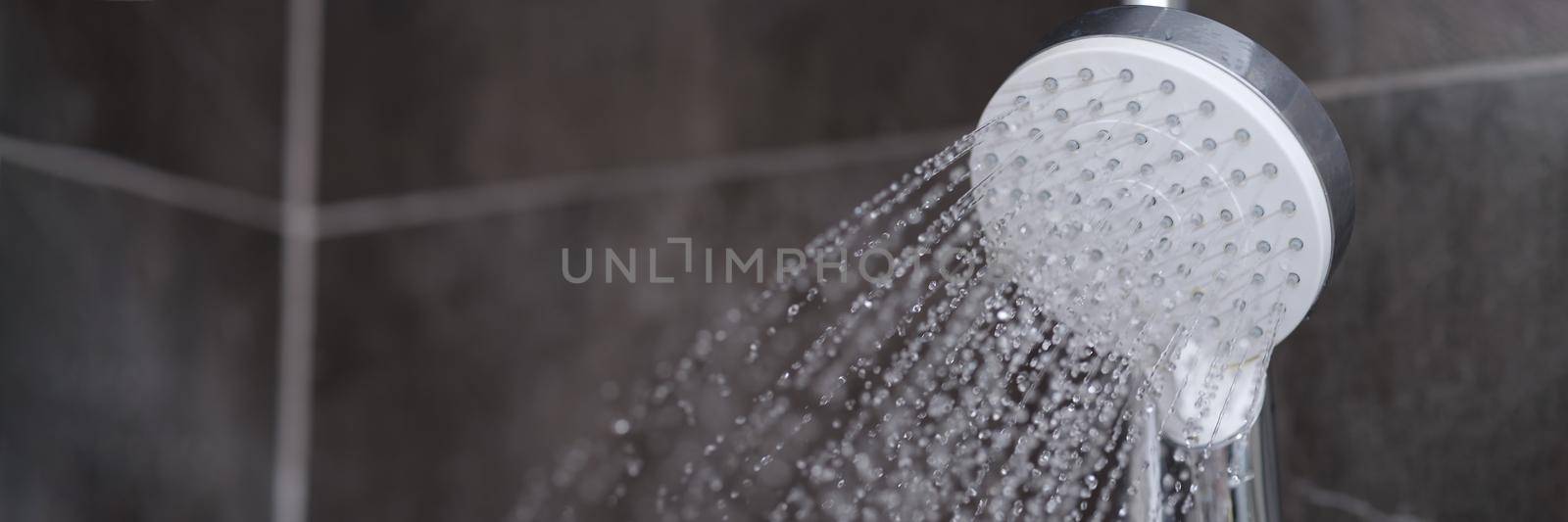 Running water pours from chrome-plated shower mixer closeup by kuprevich