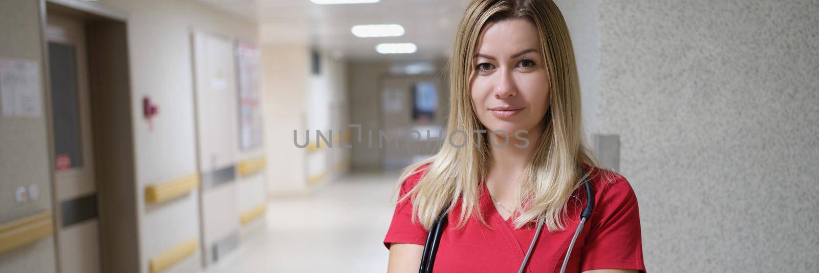 Portrait of young beautiful female doctor in red uniform and stethoscope. General doctor consultation concept