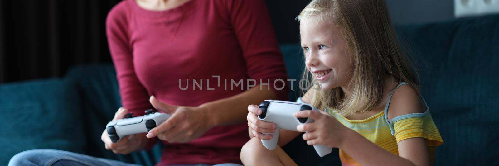 Mom and daughter play online games on console closeup by kuprevich