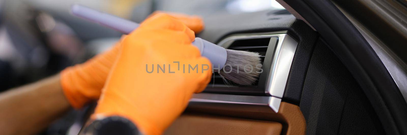 Gloved technician with brush to clean ventilation system in car closeup by kuprevich