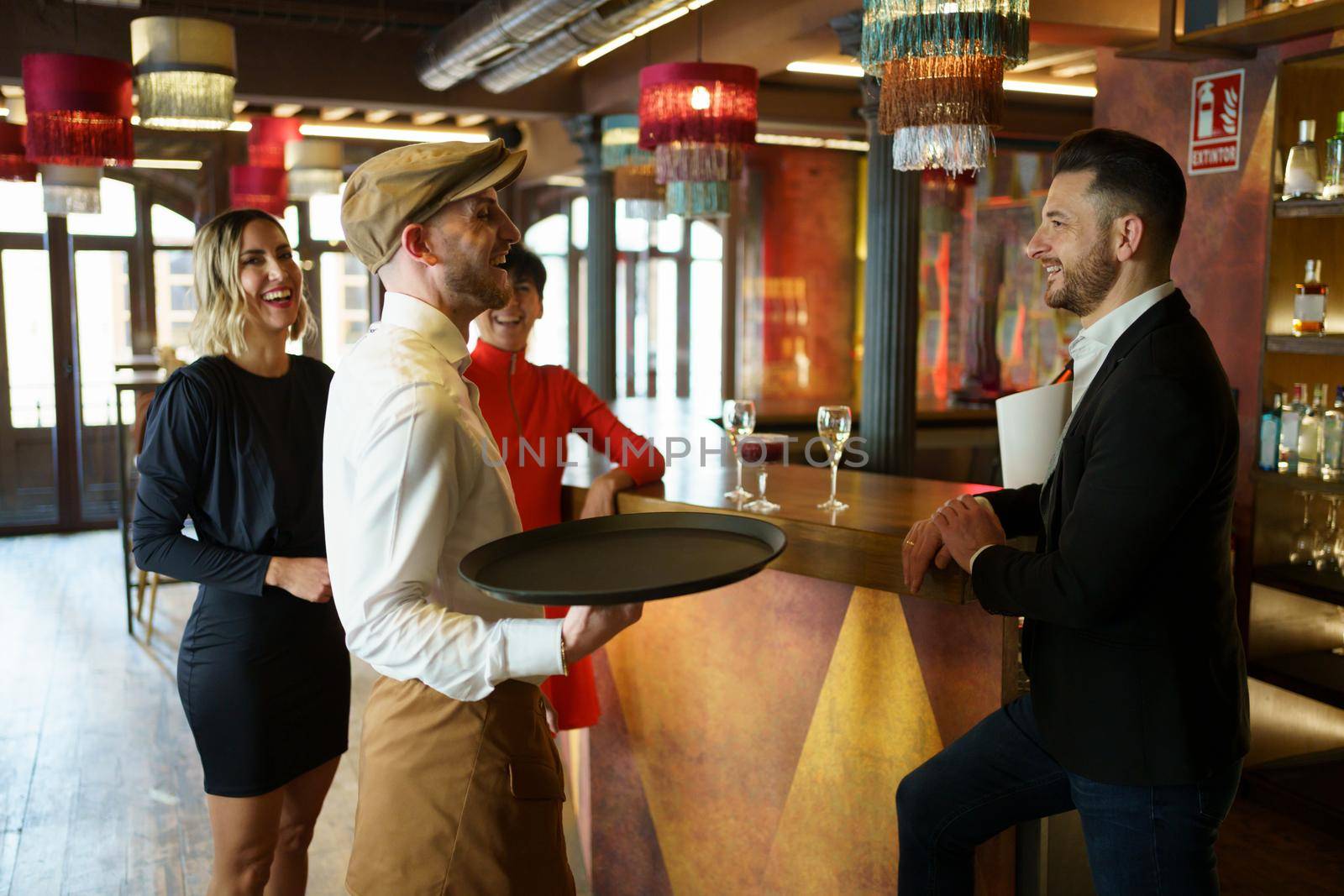 Barman serving cocktail on counter for clients by javiindy