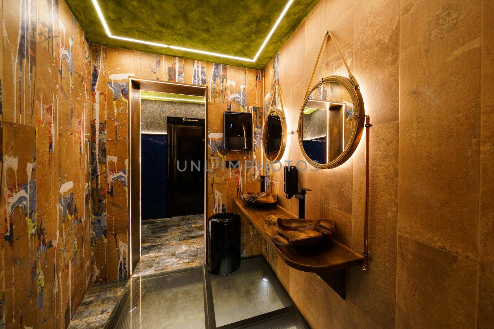 Interior of modern bathroom with opened doors and illuminated shiny walls in restaurant