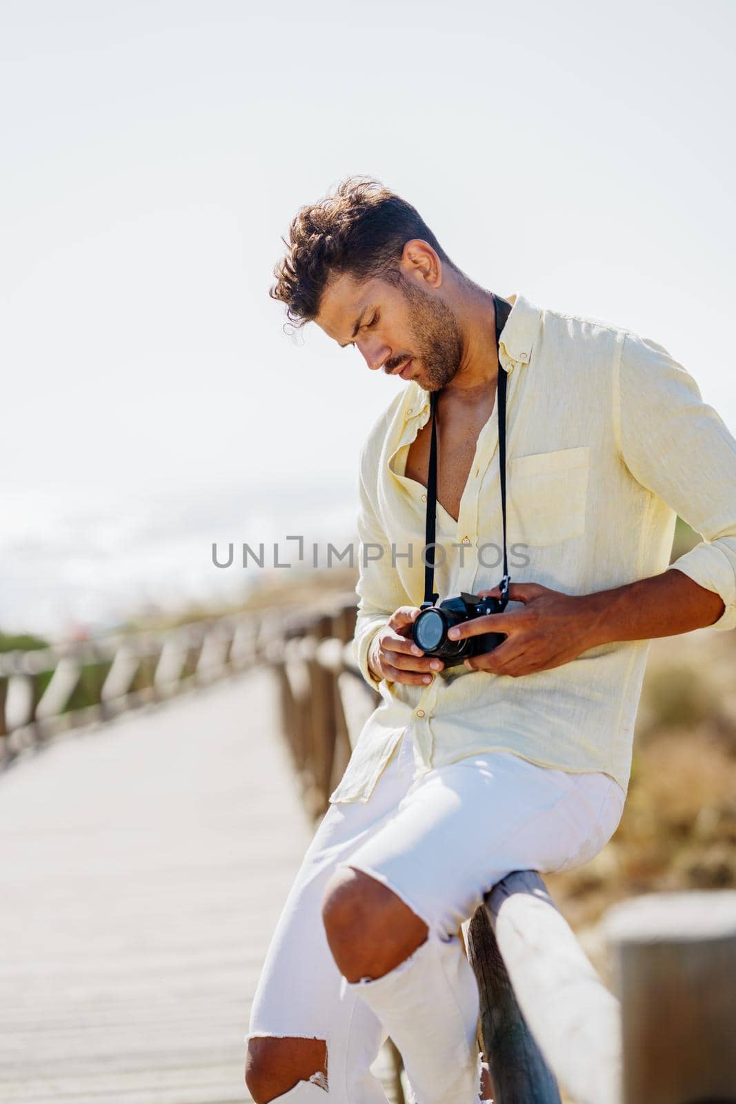 Handsome man photographing in a coastal area with an SLR camera