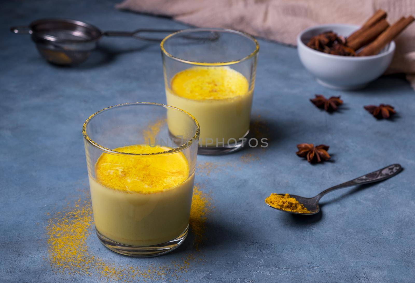 Two glasses with healthy and tasty golden milk from turmeric powder. Healing drink from India. Ayurveda. Selective focus.
