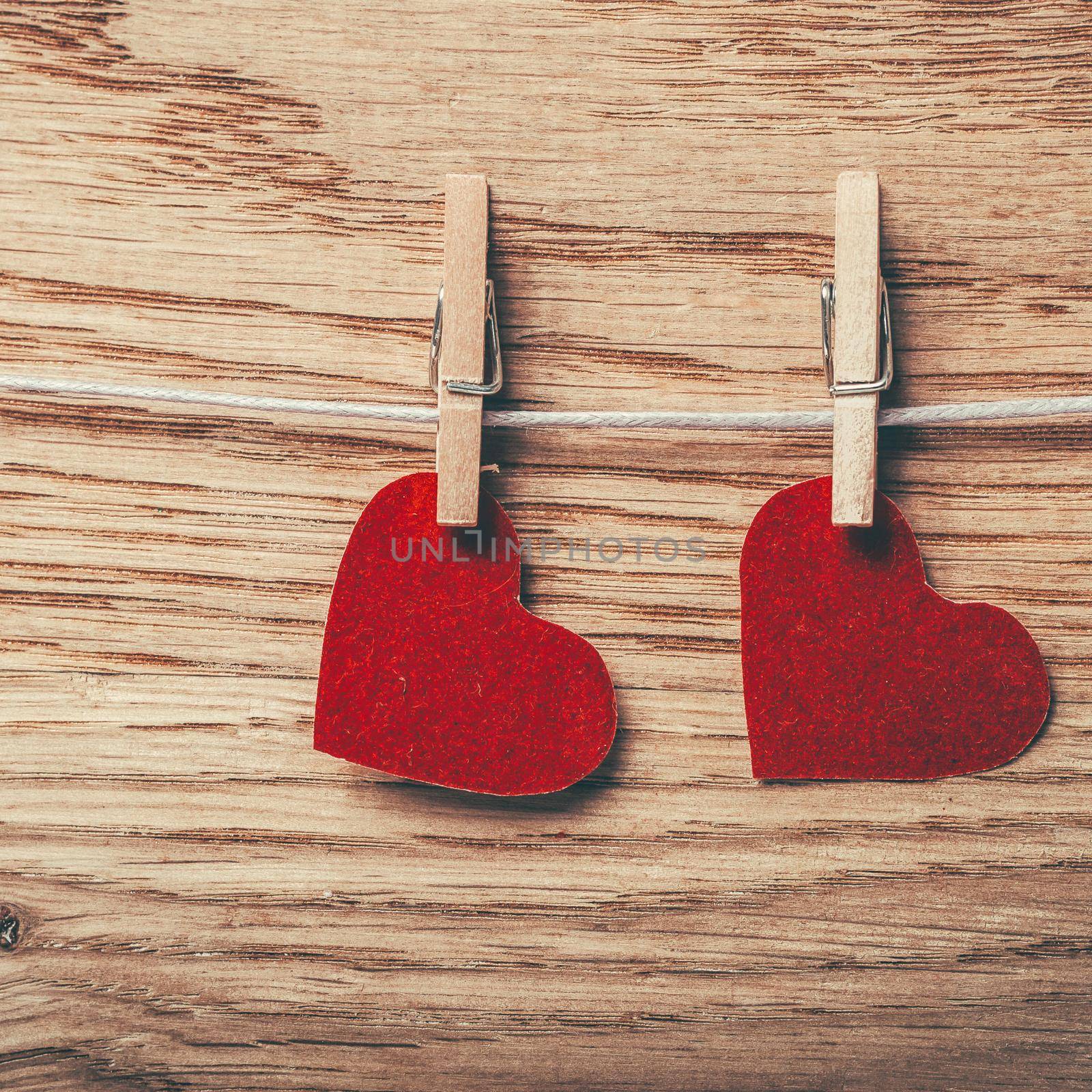 two red hearts on clothespins on wooden background . photo with copy space