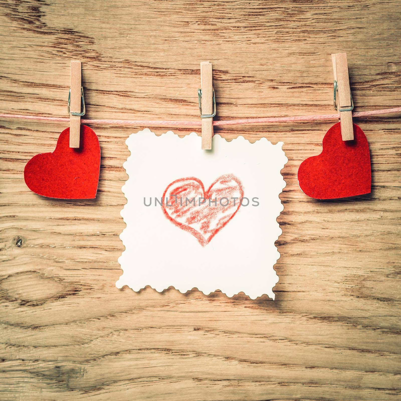 clothespins with red hearts and a blank sheet on a rope. photo with copy space