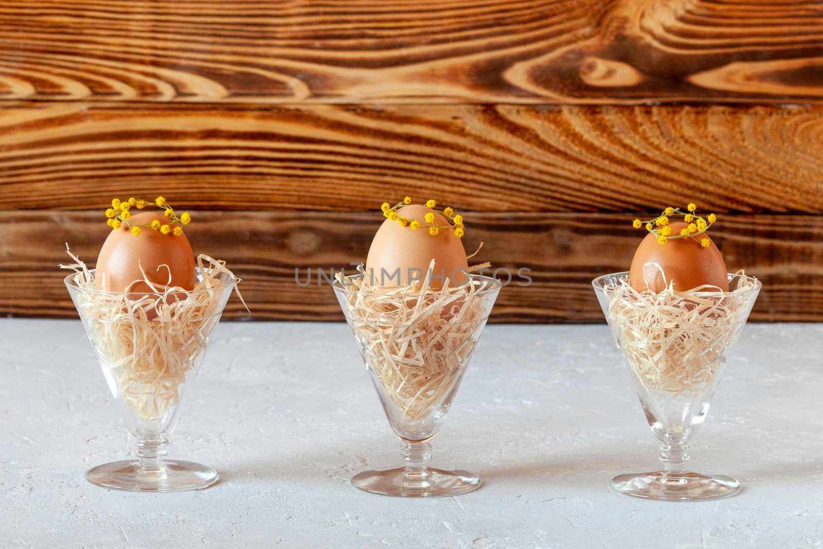 mimosa decorated chicken eggs in the straw nests in crystal glasses, idea of easy Easter table decor