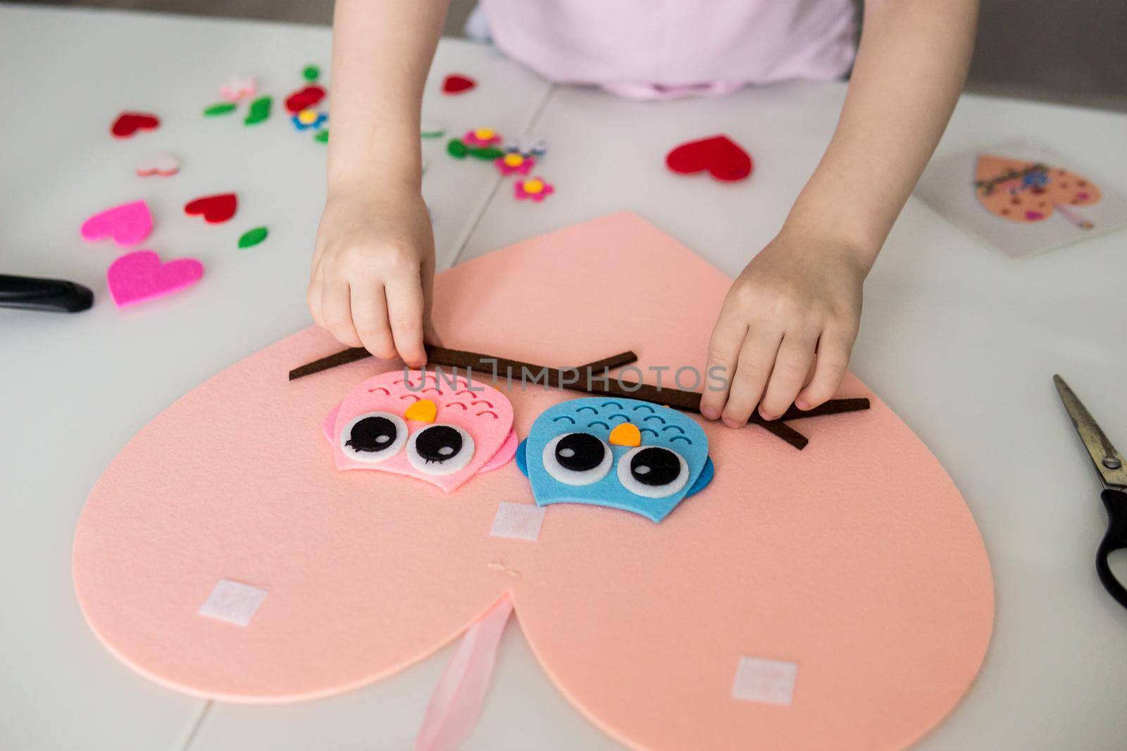 A blogger girl makes a felt craft for Valentine's Day in the shape of a heart. The concept of children's creativity and handmade.