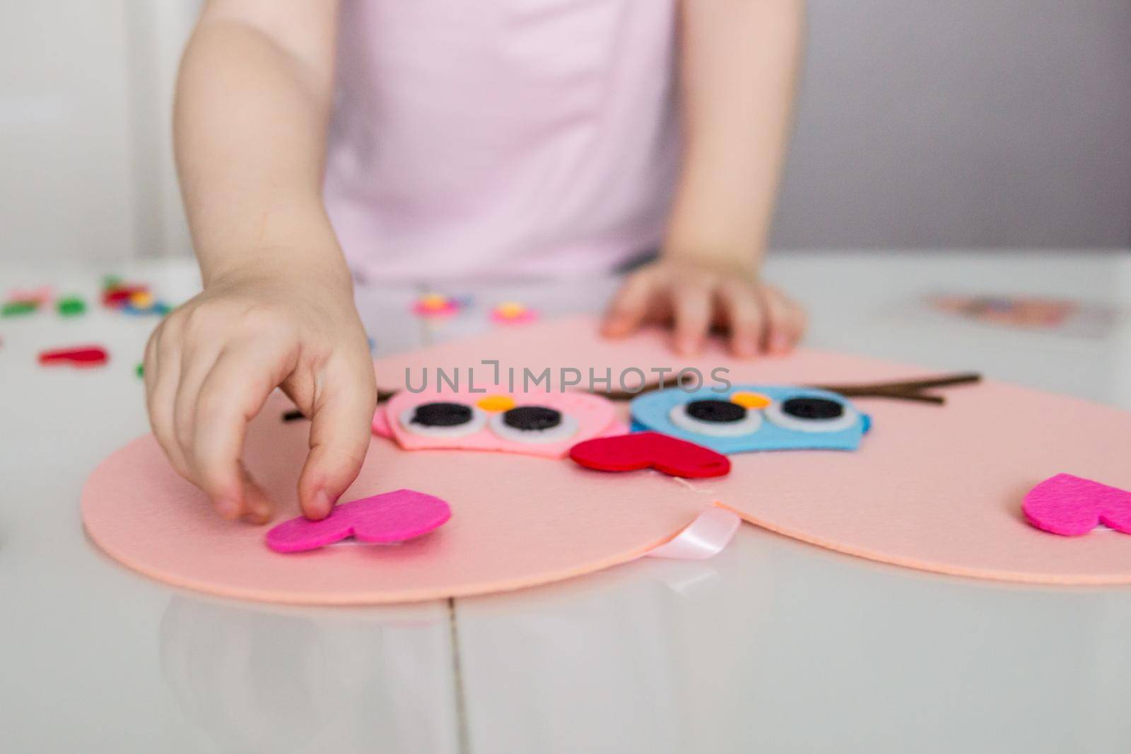 A blogger girl makes a felt craft for Valentine's Day in the shape of a heart. The concept of children's creativity and handmade.