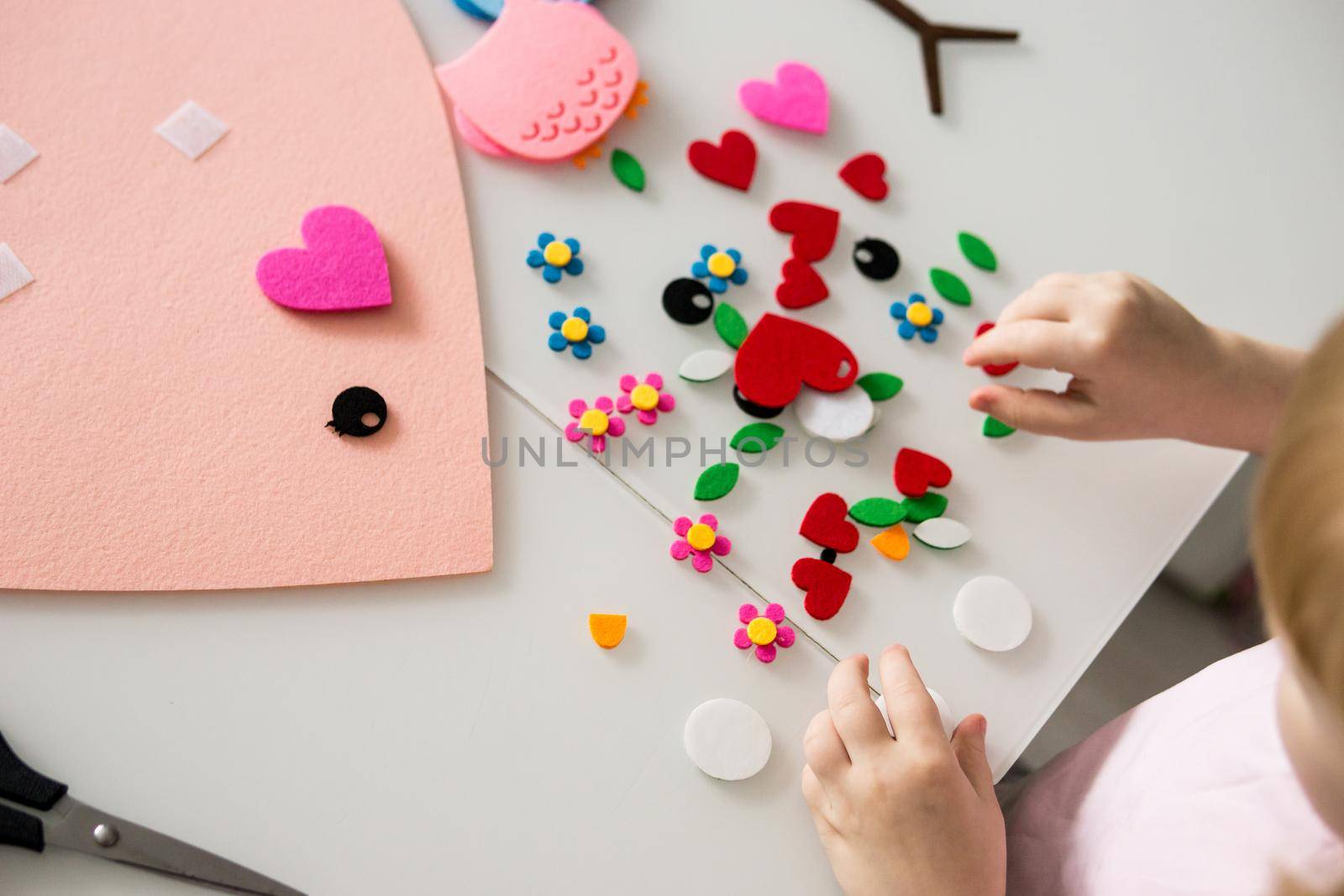 A blogger girl makes a felt craft for Valentine's Day in the shape of a heart. The concept of children's creativity and handmade.