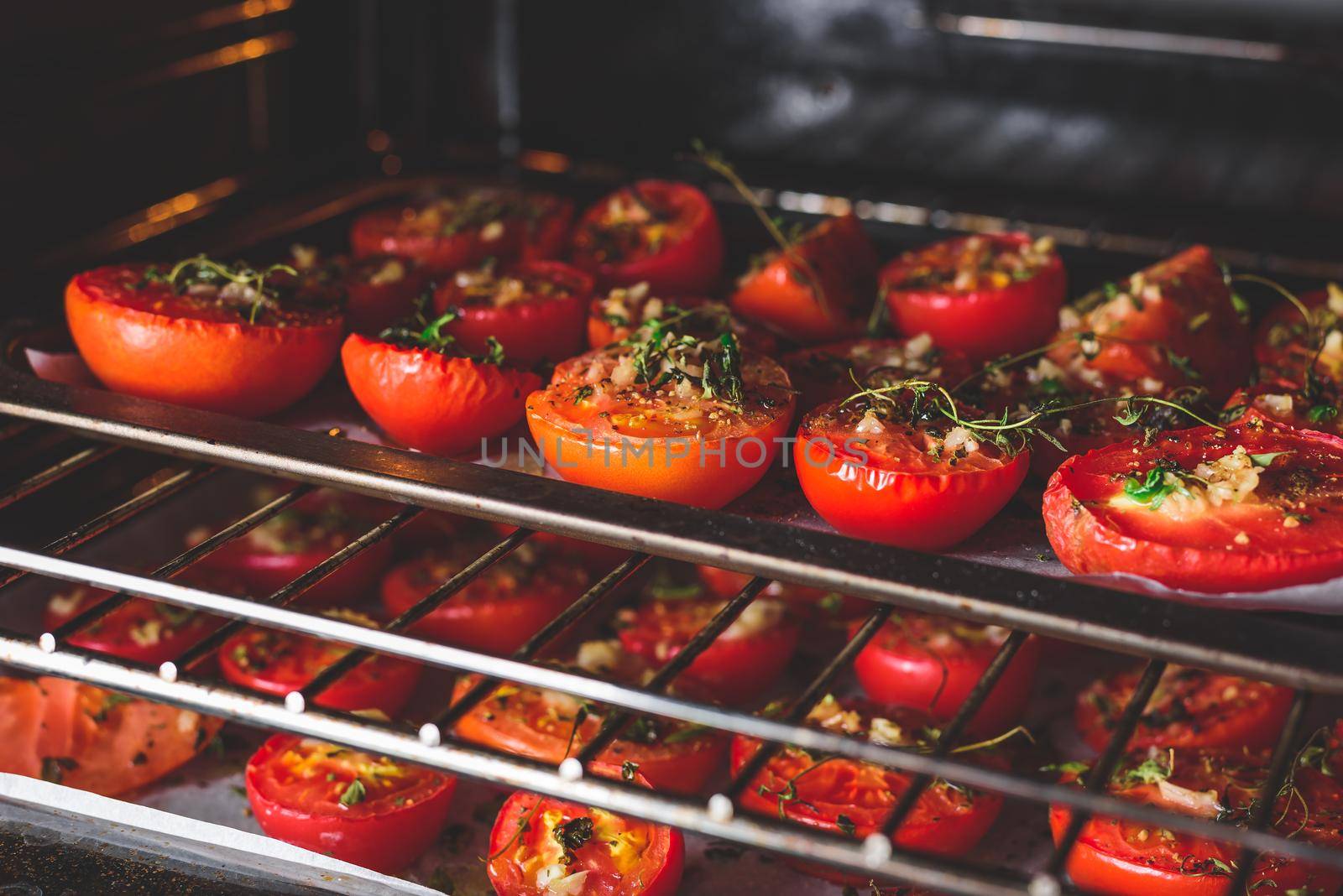 Preparing Halved Tomatoes with Herbs and Garlic on Baking Sheet in Oven for Preserving