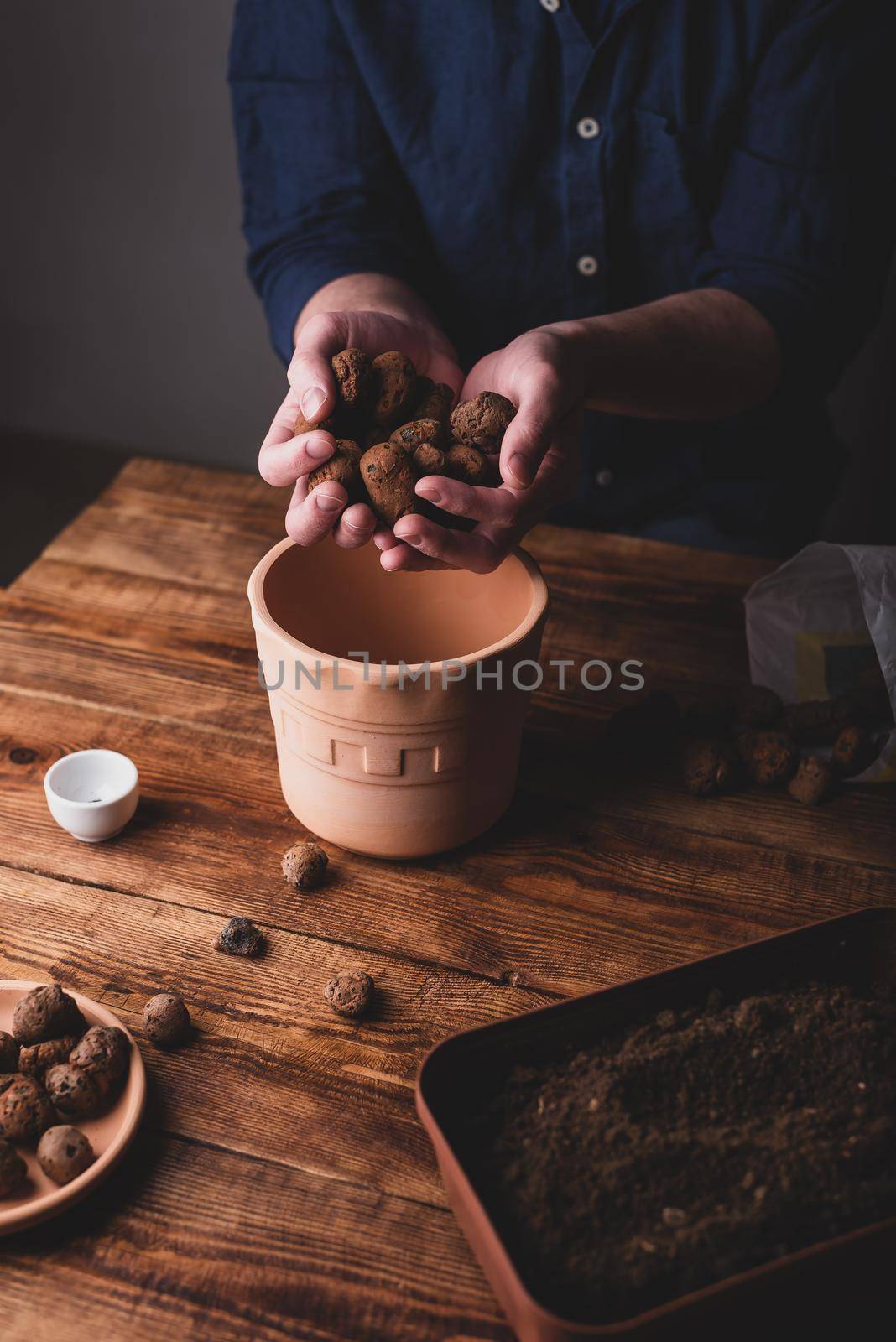 Man Putting Clay Pebbles on the Bottom of Terracotta Pot for Sowing Plant