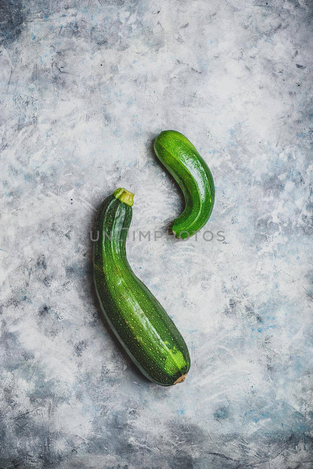 Two fresh organic zucchini on a concrete background. View from above