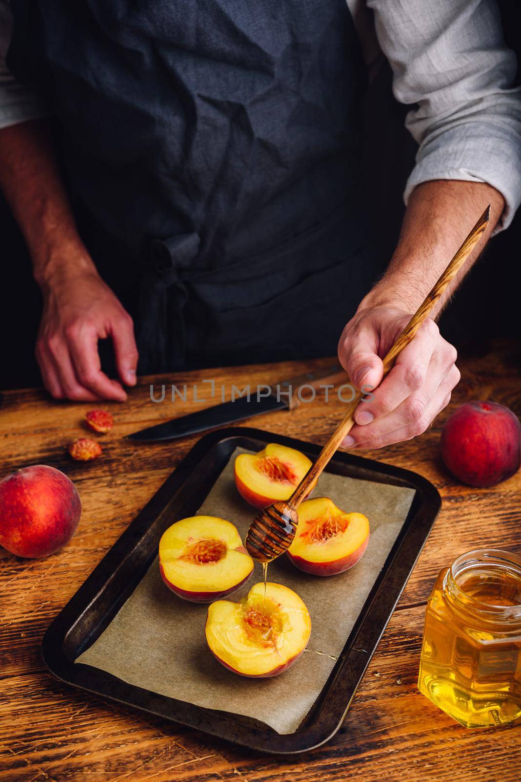 Prepare for baking halves of ripe peaches with honey. Chef pour honey over fruits