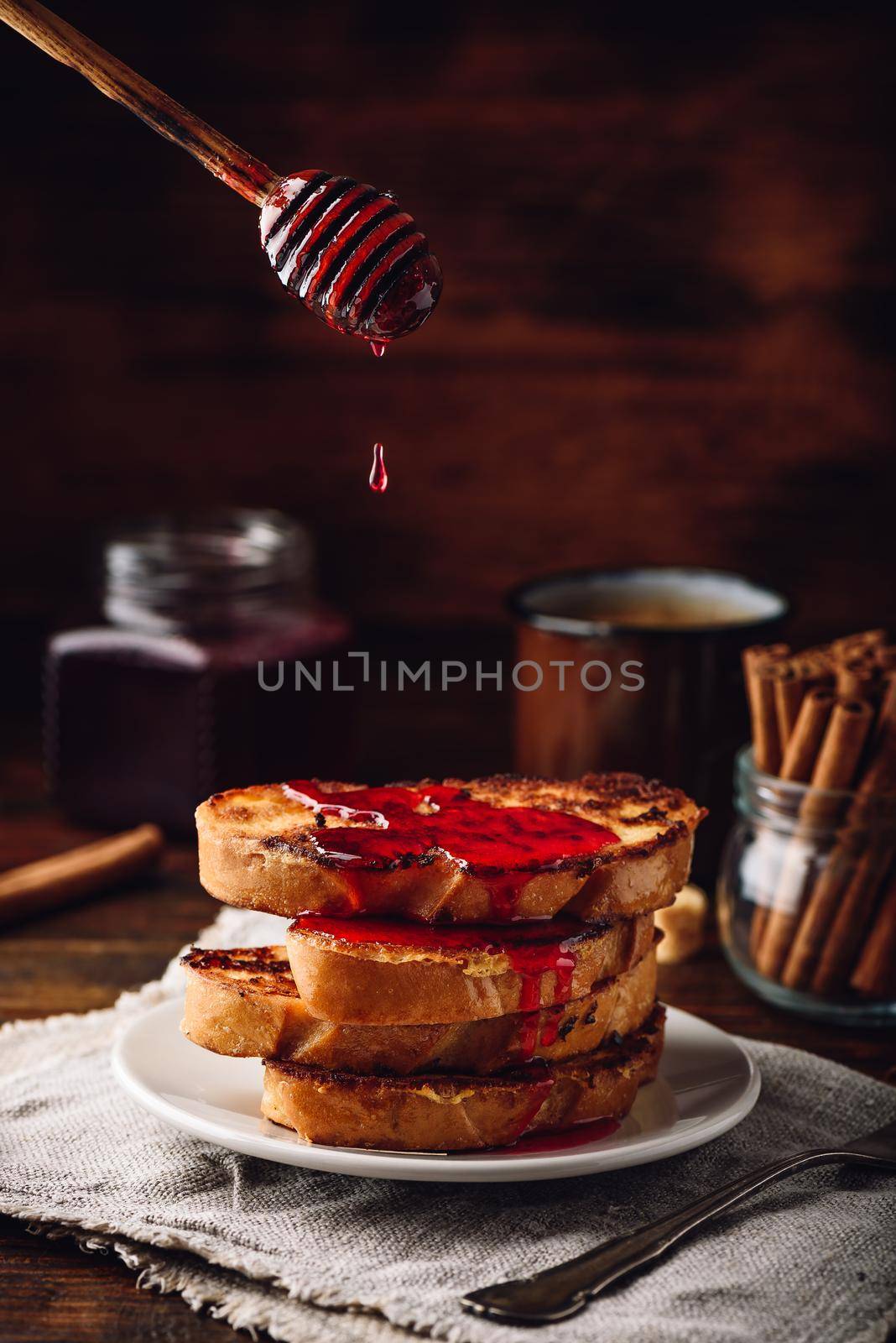 Stack of french toasts with berry syrup on white plate