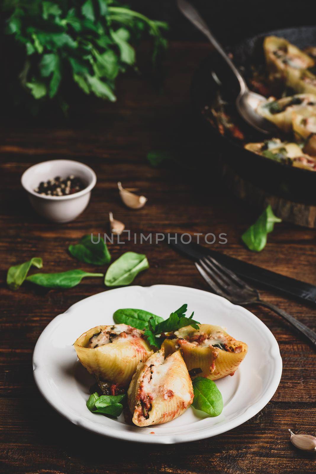 Baked shells pasta stuffed with ground beef, spinach and cheese on white plate