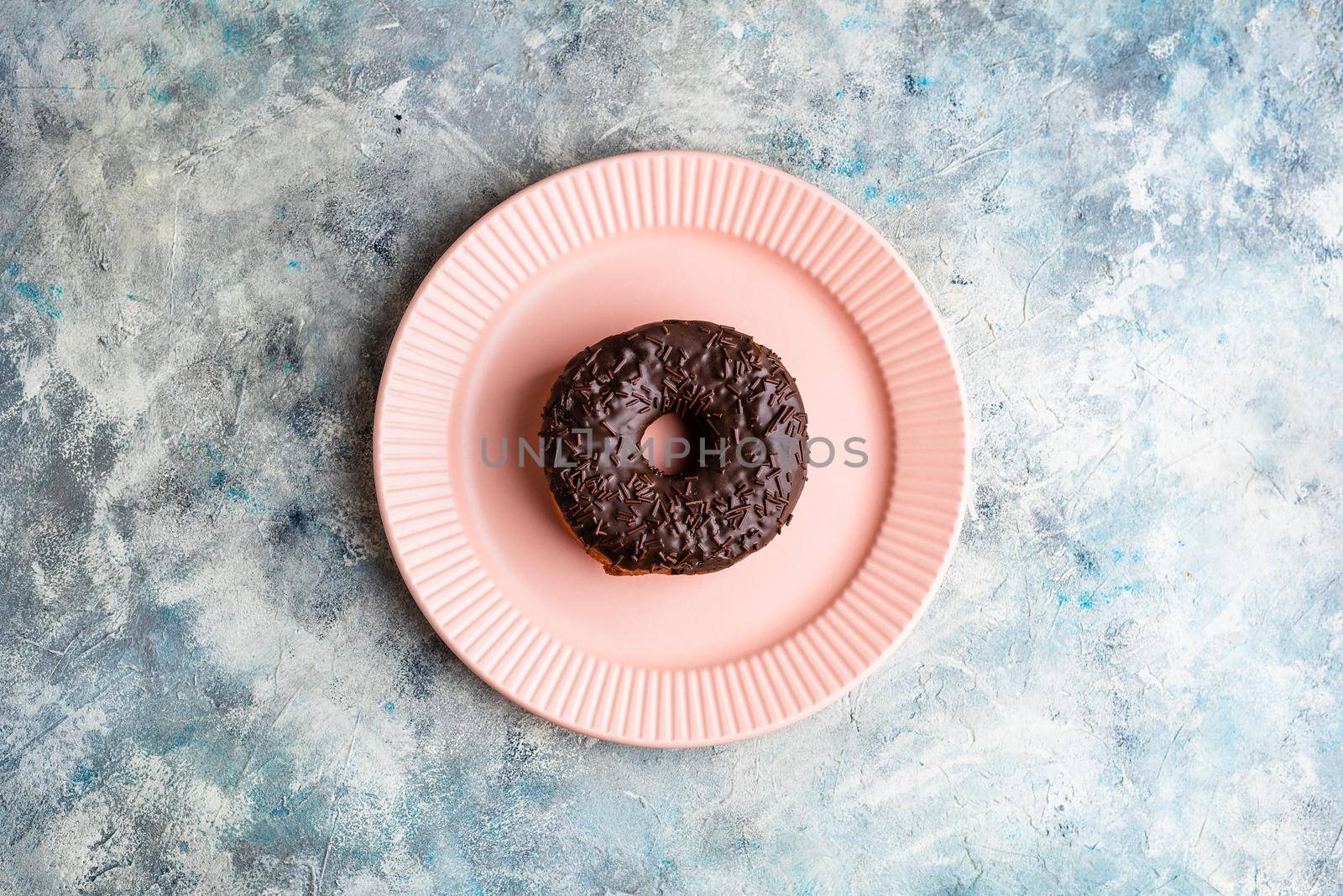 Chocolate Donut on Pink Plate. View from Above