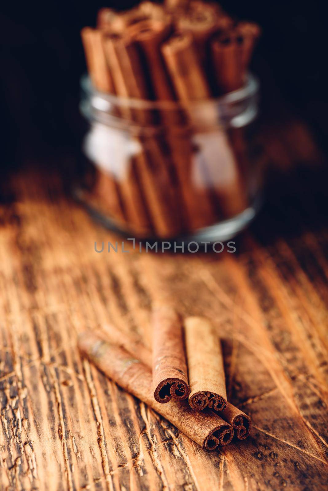 Cinnamon sticks in a glass jar over rustic wooden surface