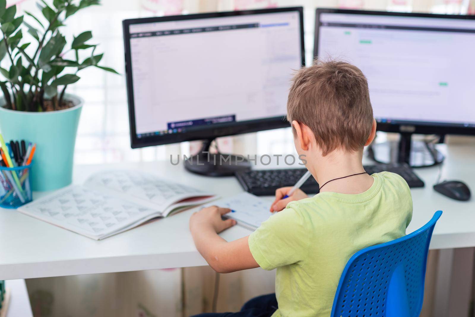 Little young school boy working at home with a laptop and class notes studying in a virtual class. Distance education and learning, e-learning, online learning concept during quarantine