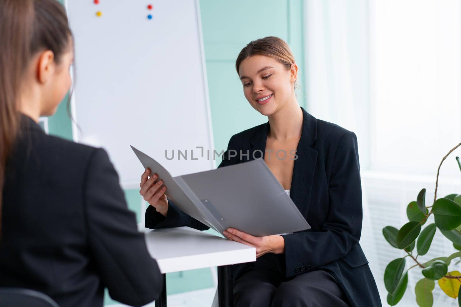 Business meeting. Young blonde woman holding contract while sitting in front of consultant during corporate meeting. Boss discuss ideas with business partner. handshaking deal