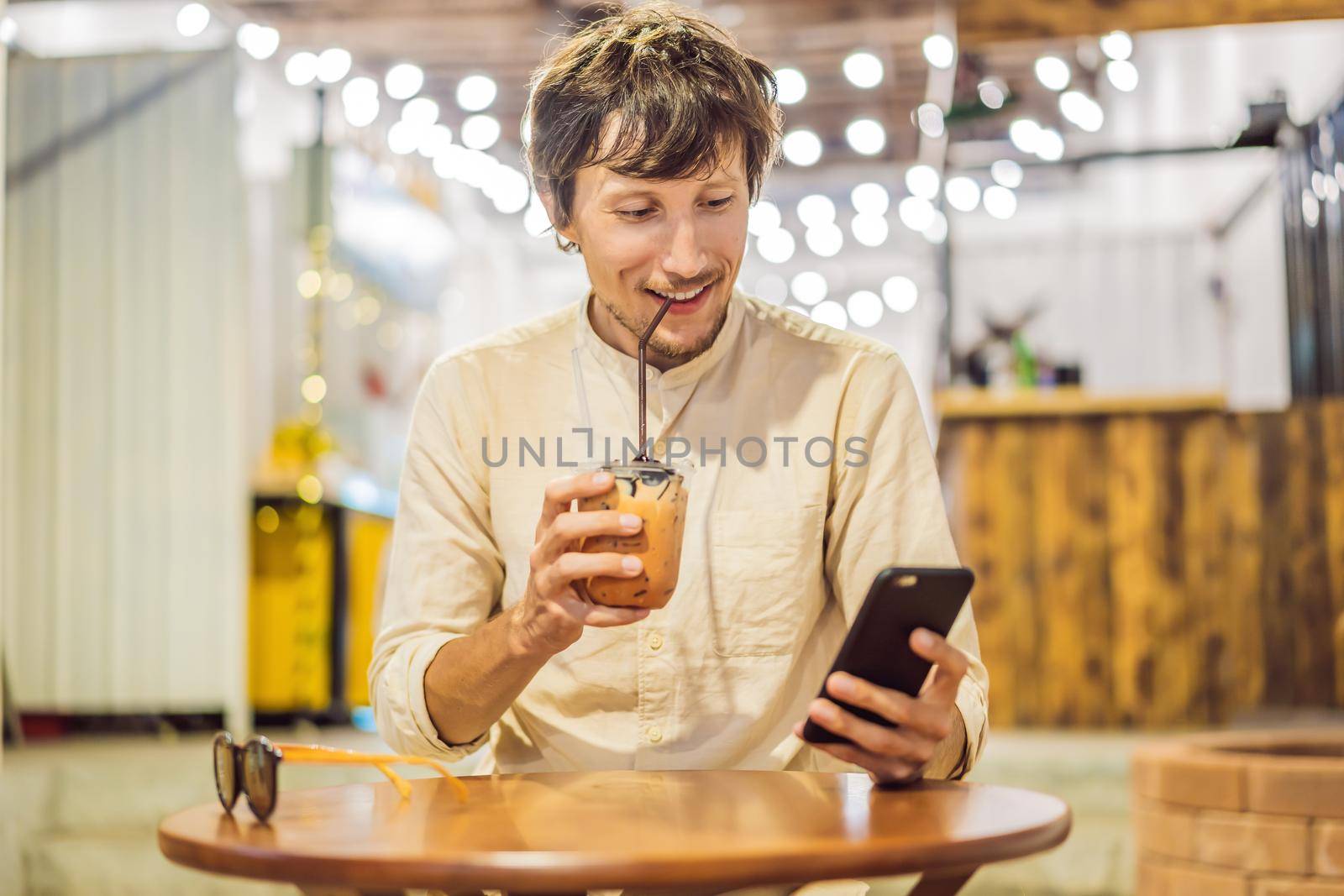 Man drinking cold bubble tea in cafe by galitskaya