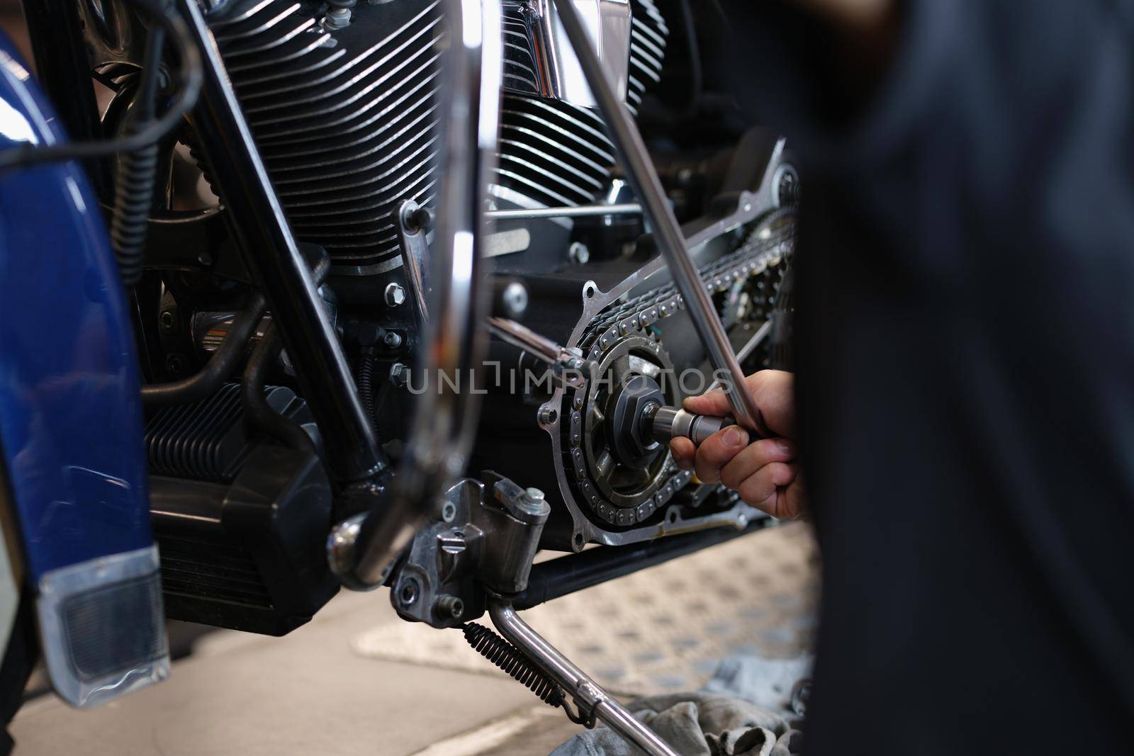 Handyman mechanic repairing part of motorbike transport with wrench equipment by kuprevich