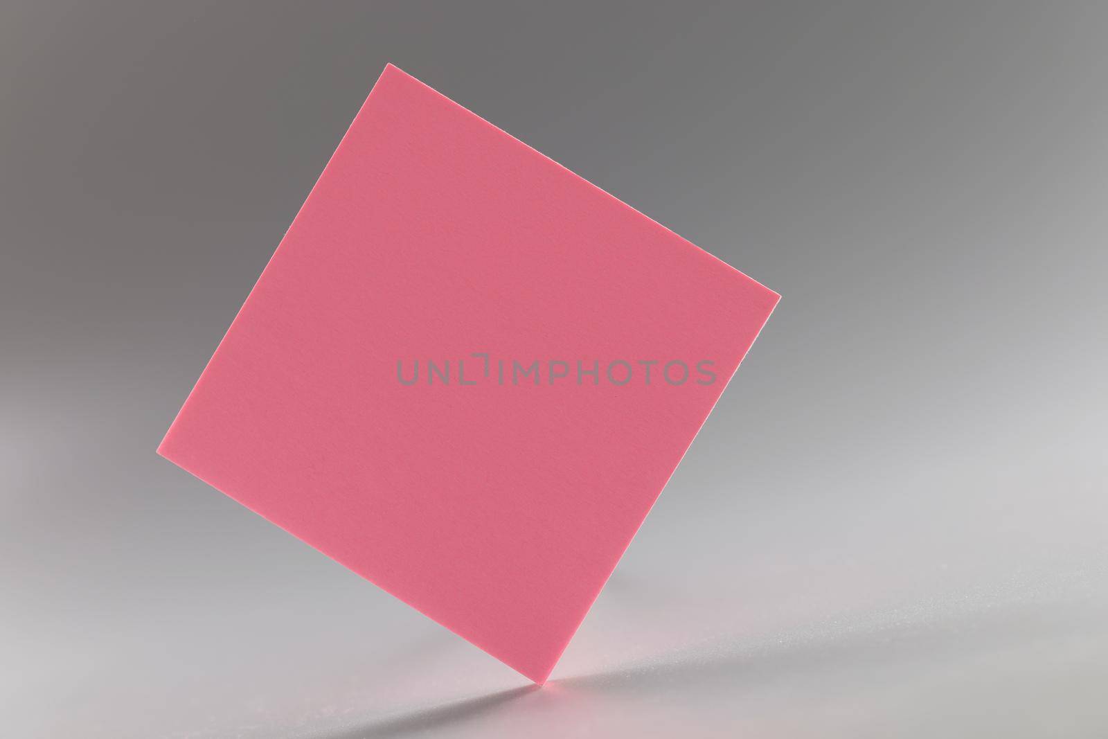 Pink square sticker standing on sharp edge on grey background by kuprevich