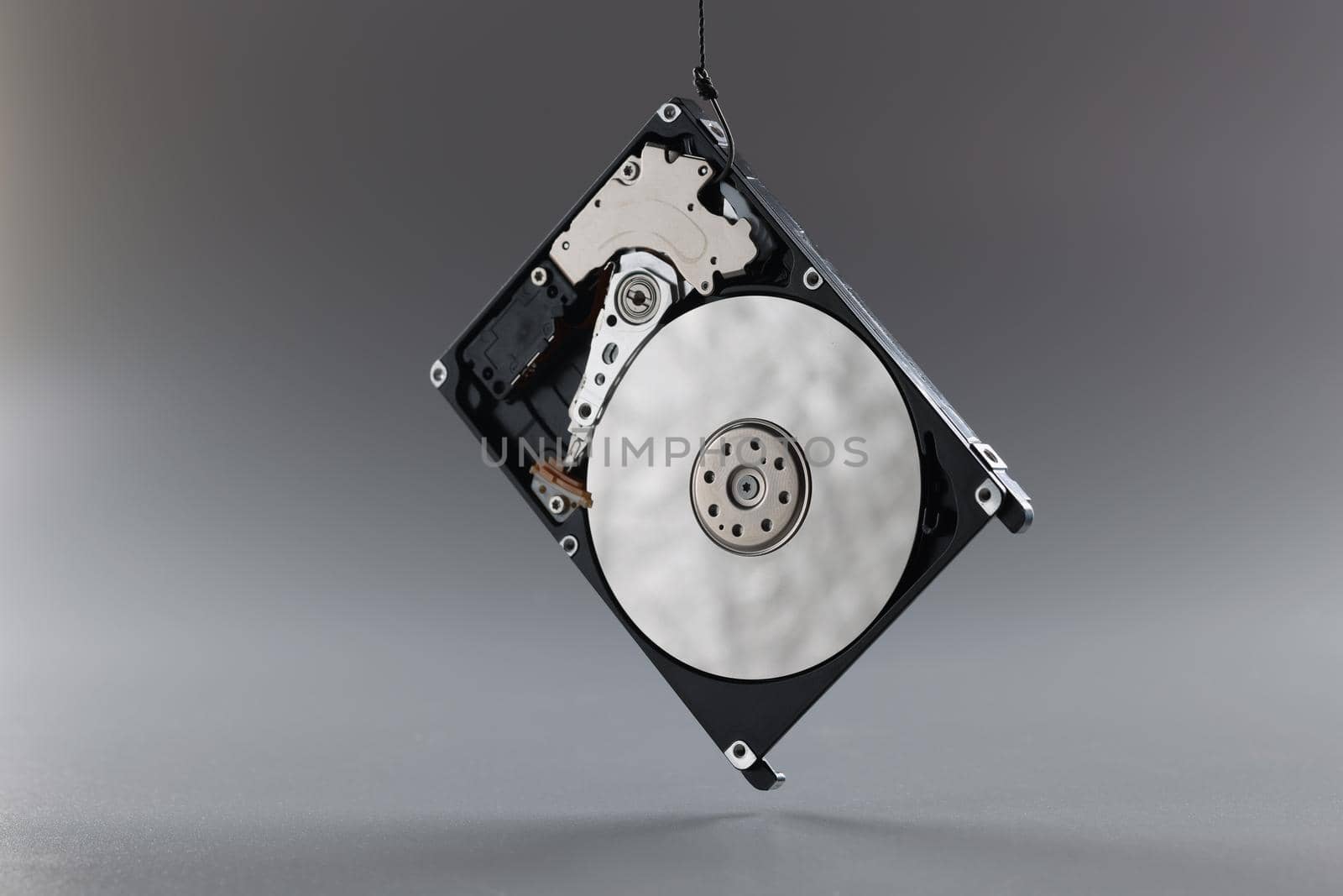 Computer hard disk drive on hook, black hardware disk, memory storage cylinder on grey background by kuprevich