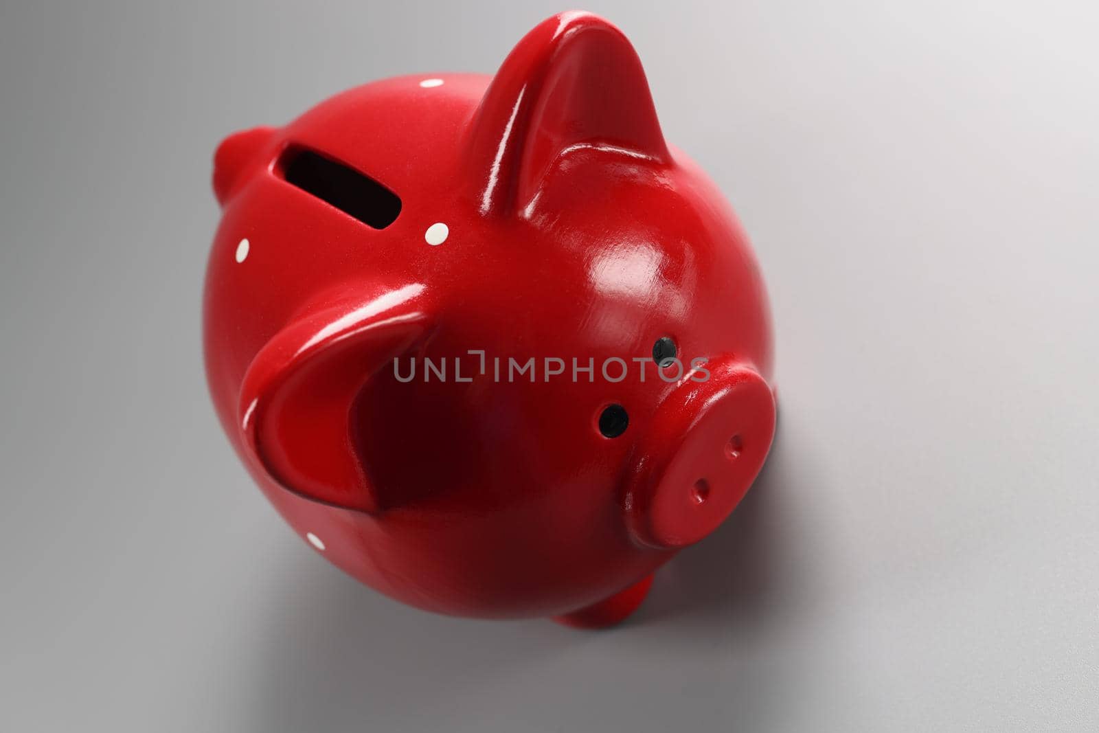 Red piggybank container on grey surface with hole for coins, empty ceramic pig for money by kuprevich