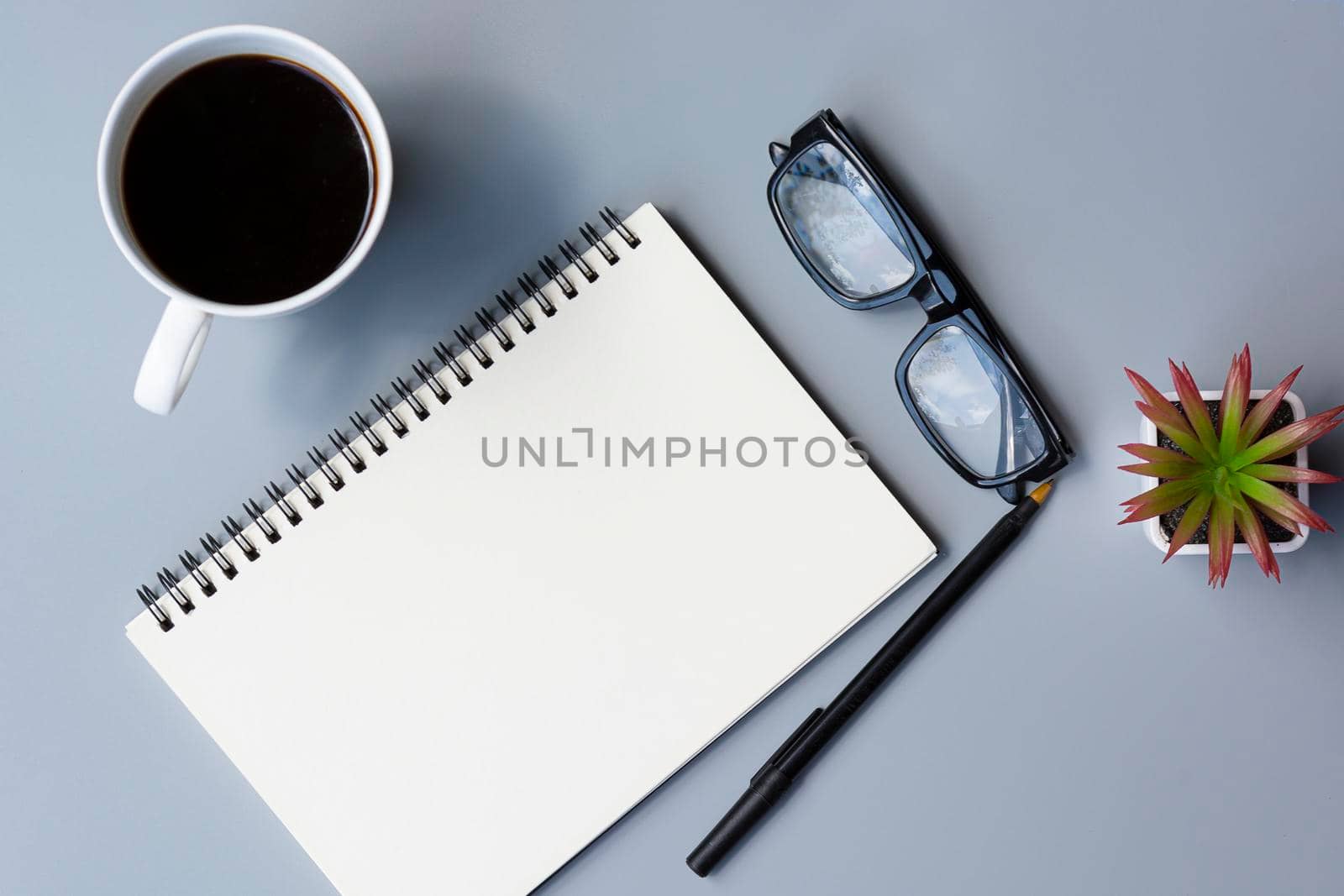 Notepad with cup of coffee and reading glasses on a desk. Directly above. Flat lay. For text usage
