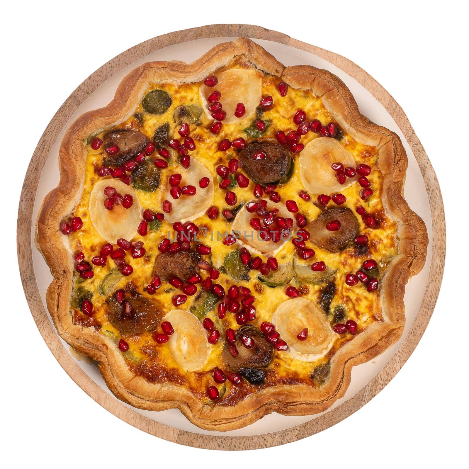 Top view of homemade vegetable quiche with goat cheese, brussels sprouts and pomegranate seeds isolated on white background.
