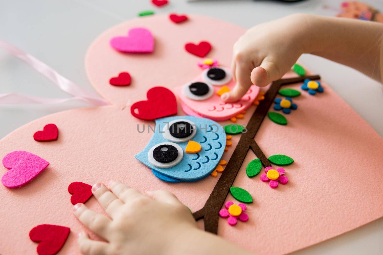A blogger girl makes a felt craft for Valentine's Day in the shape of a heart. The concept of children's creativity and handmade.