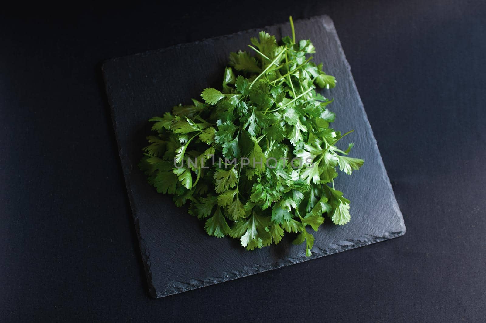 fresh dill and parsley on a black board by ozornina