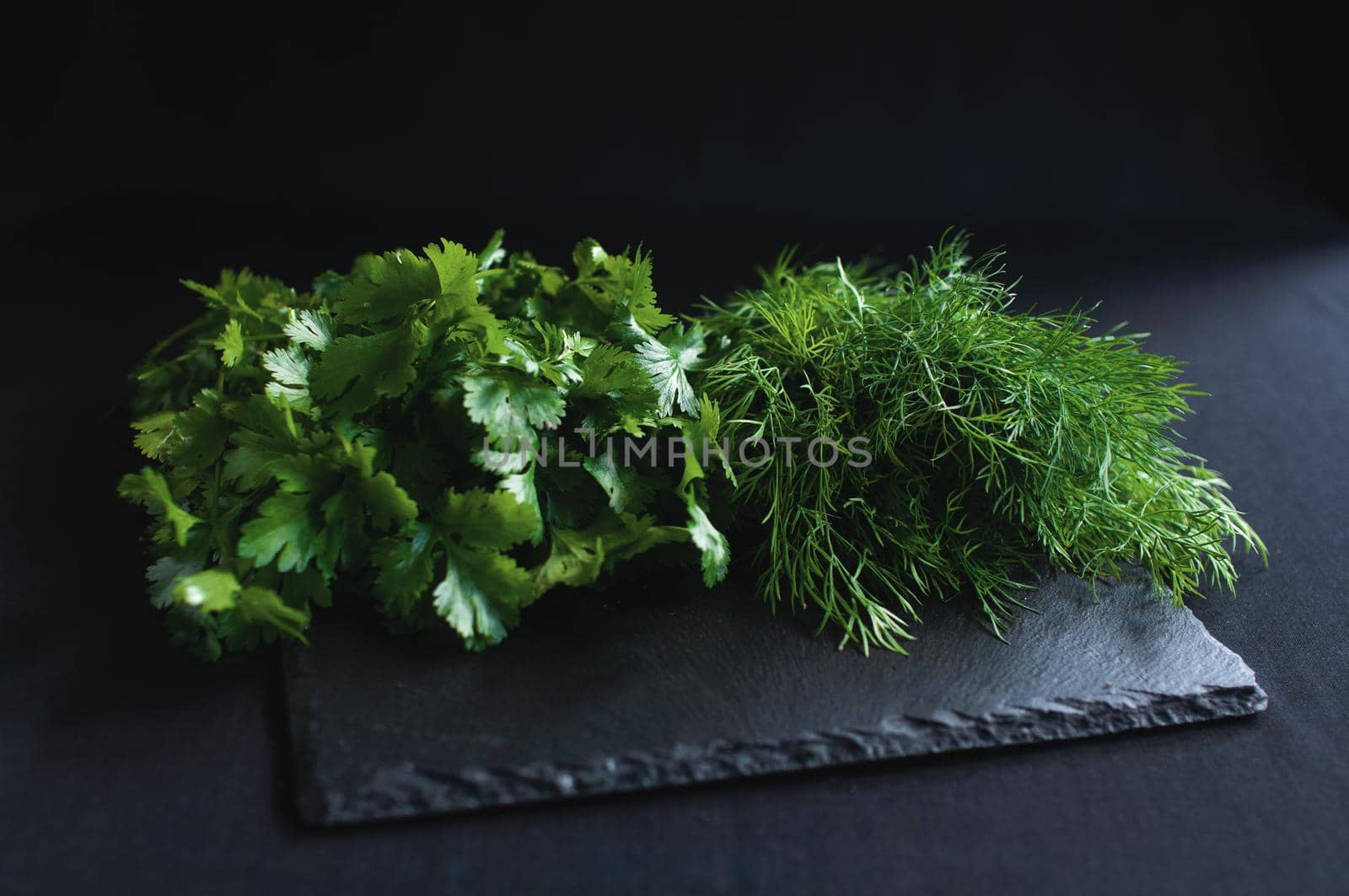 fresh dill and parsley on a black board by ozornina