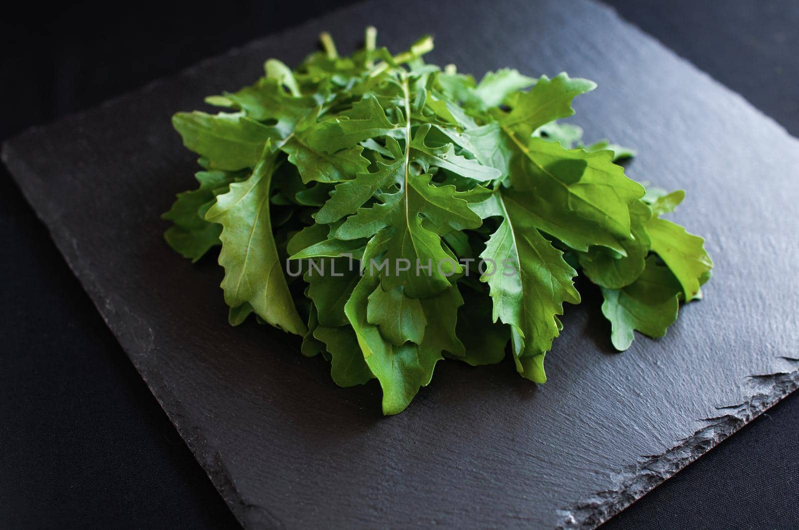 fresh arugula lying on a black board