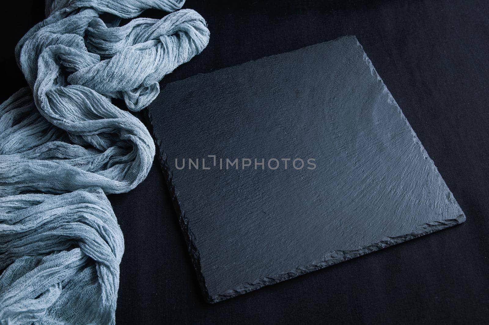 Black slate board on top view of dark stone texture with gray gauze tablecloth. by ozornina