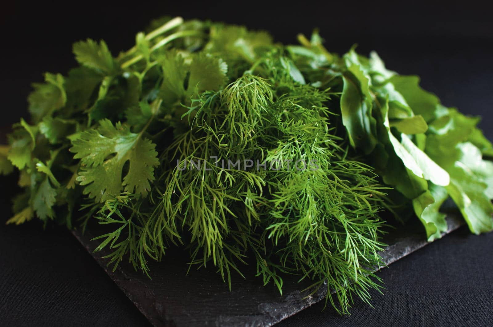 fresh arugula dill and parsley on a black board by ozornina