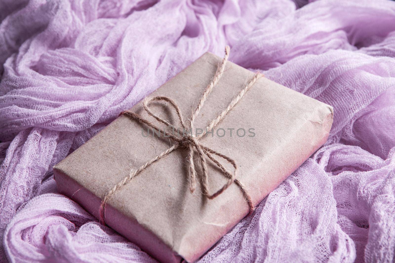 Kraft paper box next to a vintage tablecloth hand-painted with pink gauze.  by ozornina