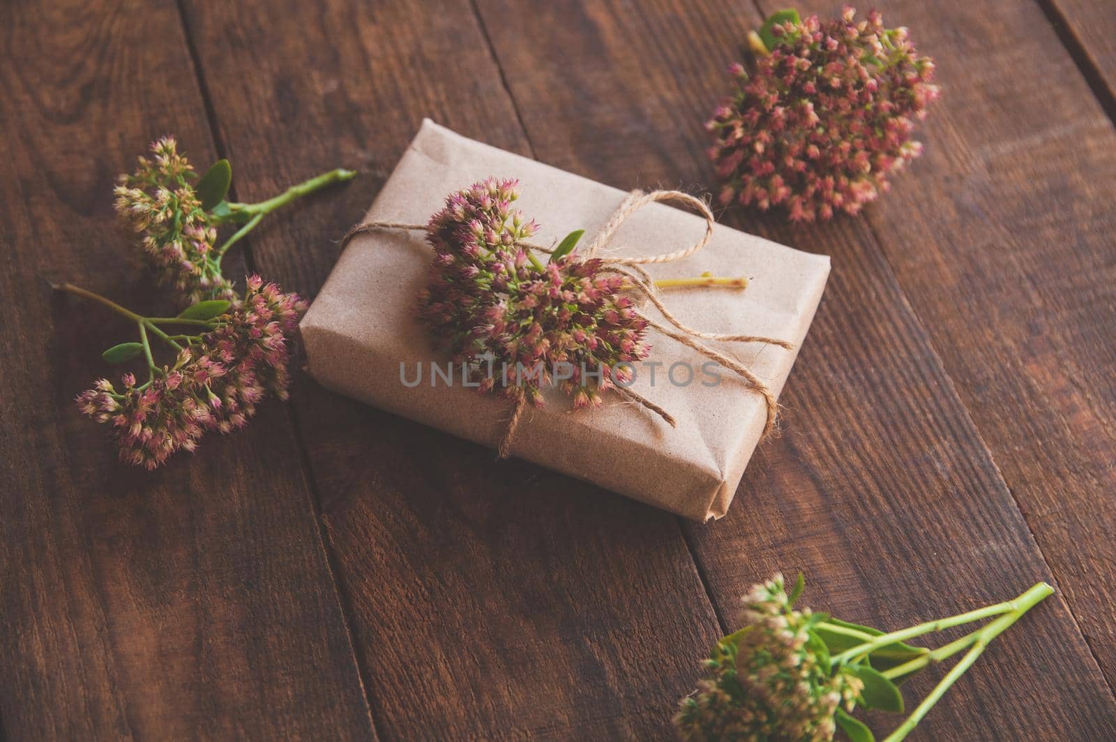 Homemade wrapped Present on a wood table. Close-up image of beautiful gift box decorated with flowers