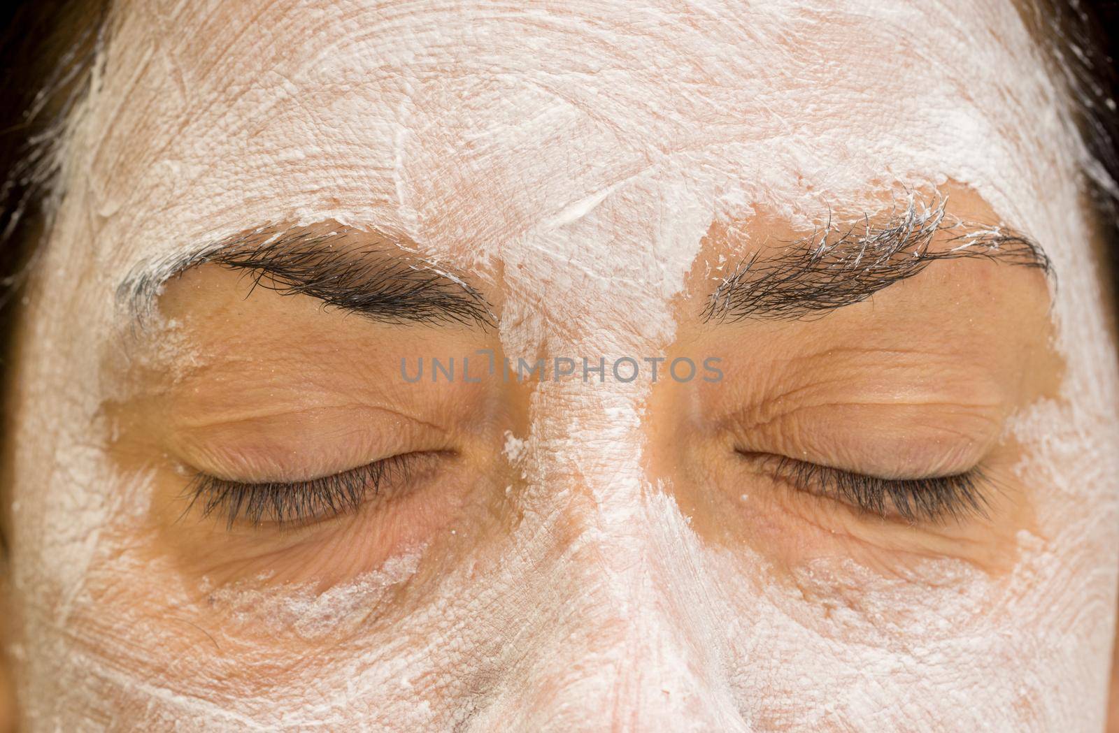 Front view of caucasian woman closed eyes and forehead with mudpack