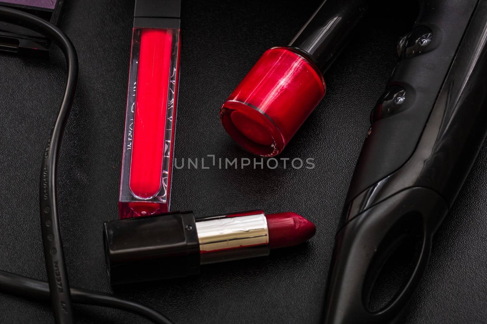 Cosmetics on a black, nail polish, eye shadow palette, lipstick, brush, parfume