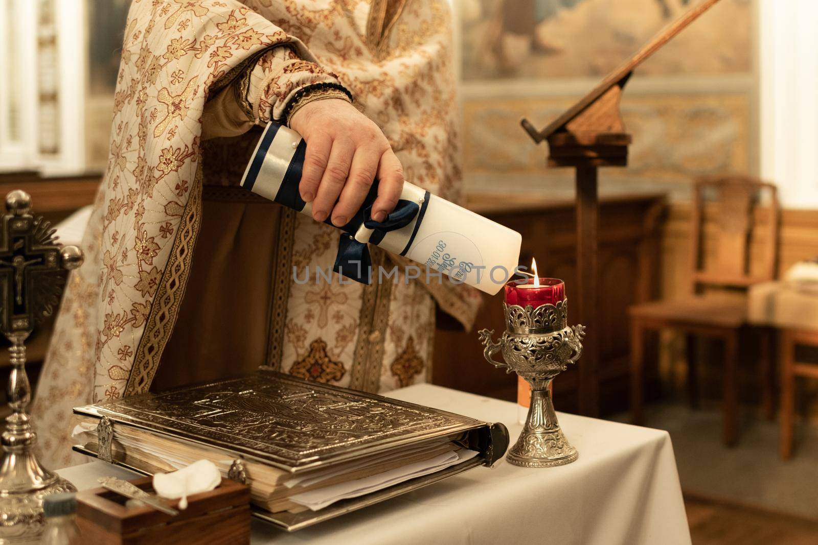 The priest lights a candle for the rite of baptism by Godi