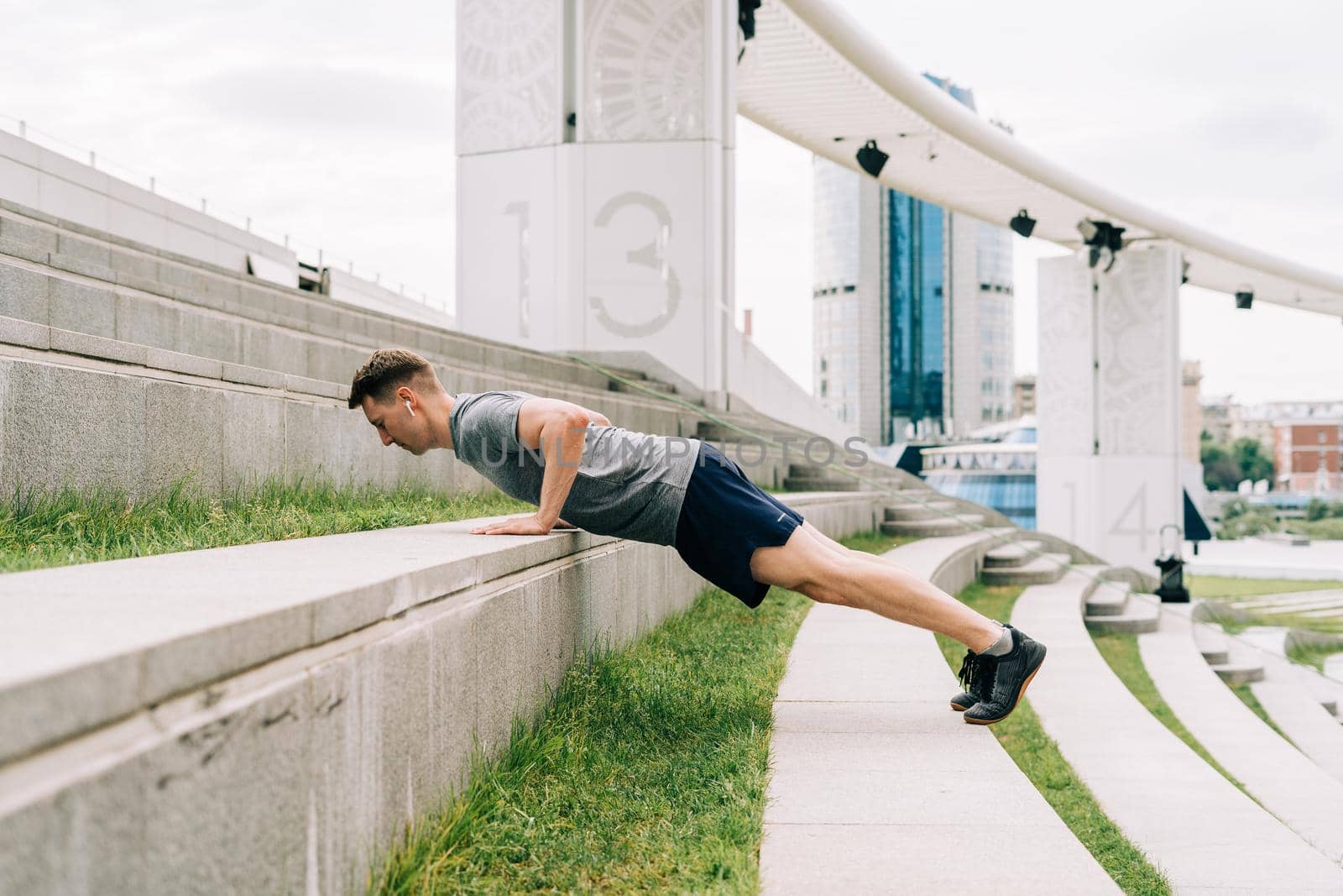 Young man has fitness workout. Male athlete does abs exercise, sport and training outdoor and stands in plank. People sport and healthy lifestyle concept.