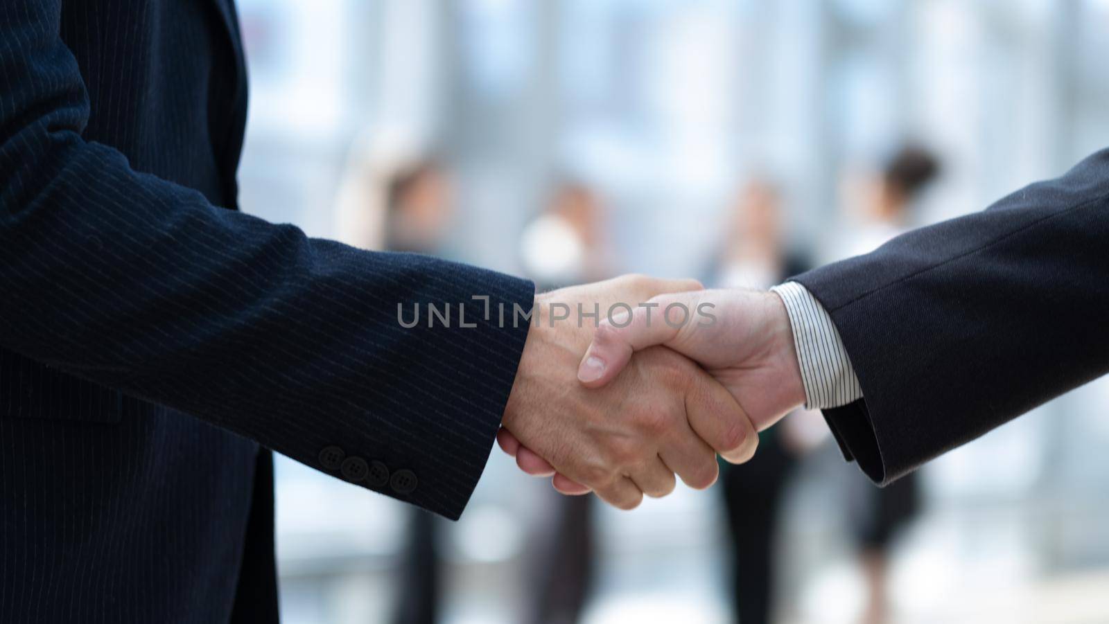 Business handshake and business people in office on background