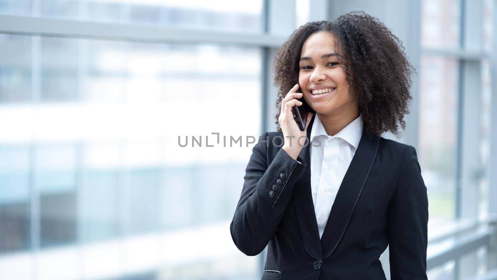 Smiling employee mixed race busines woman talking on a phone in office